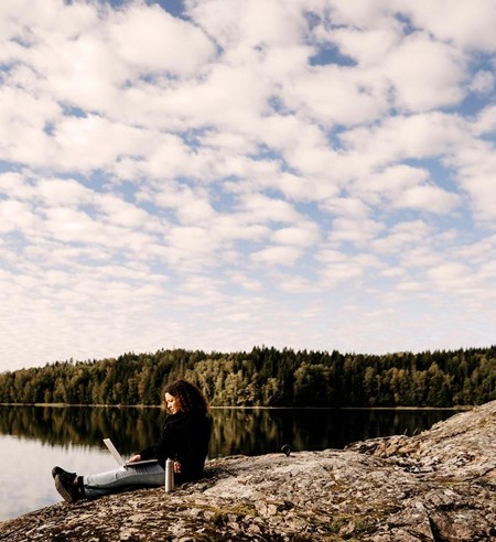 Woman working on laptop while man fishing